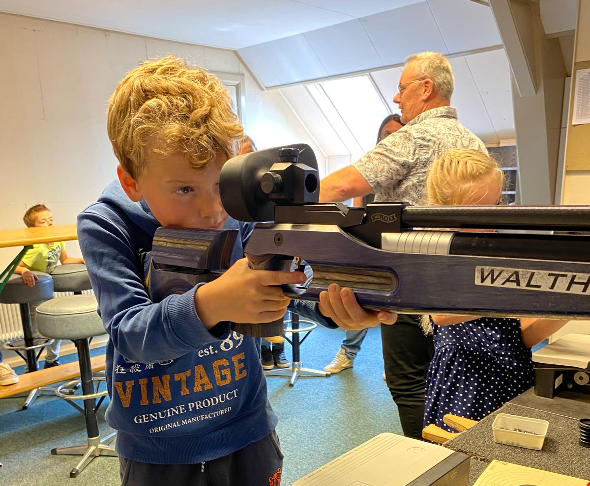 jongen die een luchtbuks vasthoudt binnen een vereniging